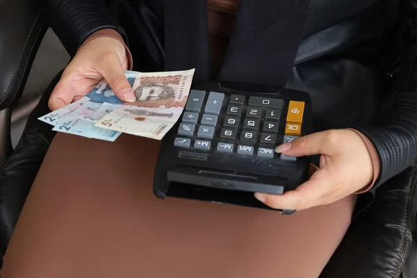 Elinde Kolombiya banknotları ve hesap makinesi tutan bir kadının elleri.