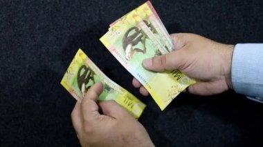 Kosta Rika banknotlarını tutan ve sayan bir adamın elleri