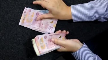 Meksika banknotlarını sayan bir kadının elleri, yukarıdan bakıldığında...