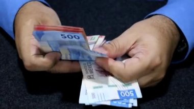 Meksika banknotlarını farklı değerlerde tutan ve sayan bir adamın elleri