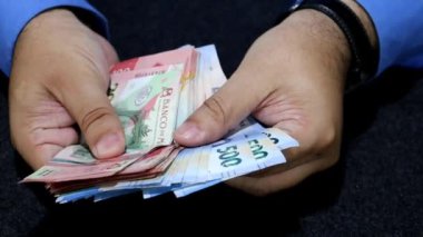 Farklı mezheplerden Meksika banknotları tutan bir adamın elleri.