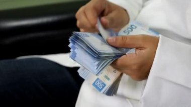 Meksika banknotlarını sayan beyaz önlüklü bir kadının ellerine yaklaş.