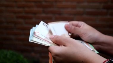 hands of a woman holding and counting European banknotes of different denomination