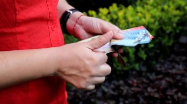 Kosta Rika banknotlarını farklı değerlerde tutan ve sayan bir kadının elleri