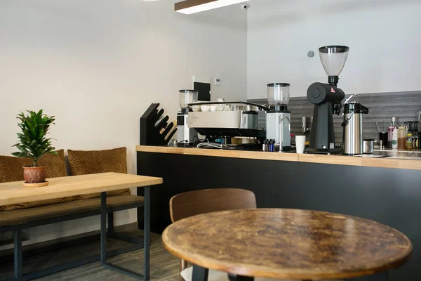 interior design of a coffee shop, coffee maker, coffee beans, a wooden bar with a wooden table and coffee cup in the background.