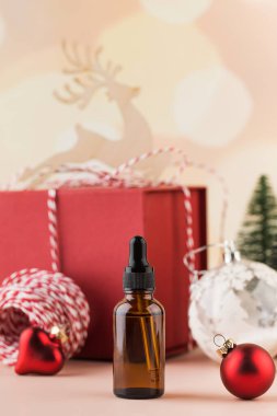 Yeni yıl arkaplanındaki kahverengi bir şişede nemlendirici serum. Noel için kozmetik ürün hediyesi konsepti. Soğukta cilt bakımı.