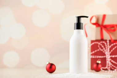 Karda kozmetik ürünü olan beyaz bir kutunun maketi Noel hediyelerinin arka planında. Yeni yıl hediyeleri. Boşluğu kopyala.