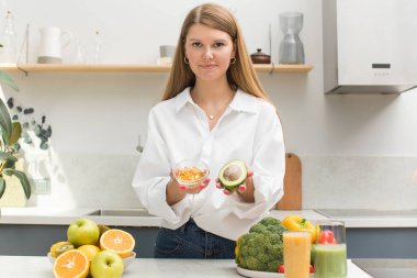 Kadın avokado ve D vitamini ve omega-3 içeren sarı kapsüller tutuyor. Sağlık ve diyet kavramı.