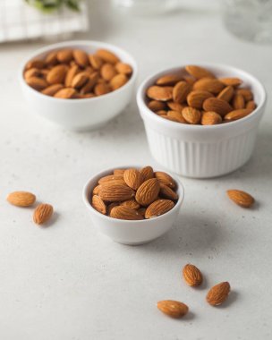 Hafif beton arka planda kavrulmuş bademler. Sağlıklı atıştırmalık kavramı, fındıktan yağ tüketimi..