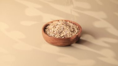  Kuru yulaf ezmesi ahşap bir kaseye dökülür. Sağlıklı kahvaltı, sağlıklı beslenme kavramı. Glüten..