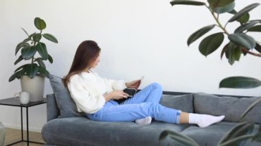 Çekici, genç, esmer bir kadın evinde dizüstü bilgisayarla çalışıyor. Uzaktan öğrenme, bilgi alma, bir dizüstü bilgisayar kullanarak.