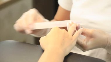  Bir manikürcü, O.P.I. dosyası ile tırnaklarını törpülüyor. Güzellik salonunda manikür işlemi. Yüksek kalite 