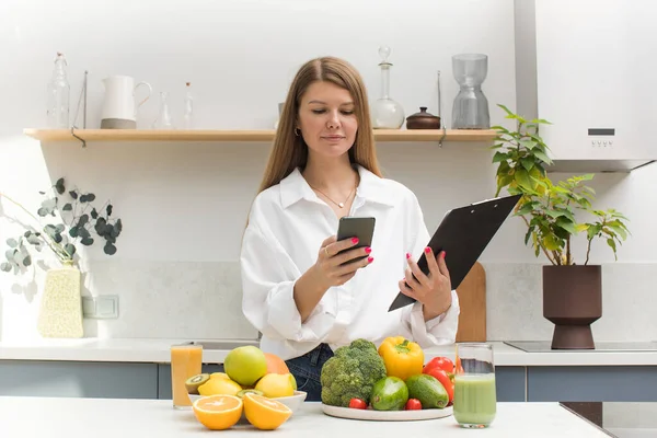 stock image The nutritionist stands at the table with vegetables and fruits and makes a meal plan for the client. The concept of weight loss, healthy eating.