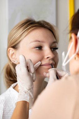 Usta, dudak daimi işleminden önce fırçayla bir eskiz çizer. Dudakların sınırlarını çizme süreci..