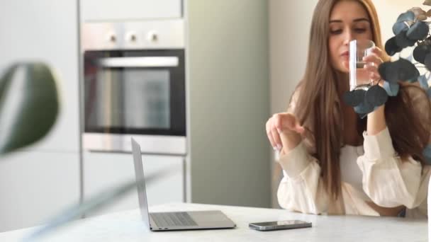 迷人的女人坐在笔记本电脑前 一边喝着杯子里的水 良好的习惯和健康的生活方式 — 图库视频影像