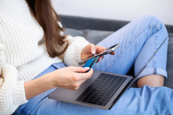 Online payment, a woman holds a smartphone and uses a credit card for online purchases. The concept of online shopping, online payment using a laptop computer