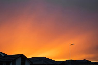 Yeni Zelanda 'daki evlerin çatısında renkli bir günbatımı. Renkli manzara.