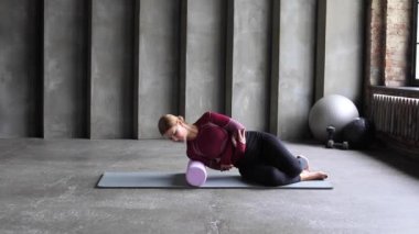 Bir fitness eğitmeni omuz kaslarının gevşemesi ve omuz kaslarının yenilenmesi için bir silindir ile miyofasyal gevşemesini gösterir. MFR, pilates, rehabilitasyon. 