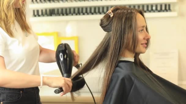 美容師はヘアドライヤーと丸い櫛でクライアントの髪を乾燥させます 美容室 — ストック動画