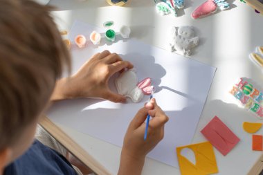 Bir çocuk Paskalya tavşanı heykelciği çiziyor. Çocukların yaratıcı gelişimi, çocuk el sanatları kavramı. Paskalya çocukları el sanatları.