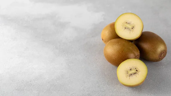 Golden yellow kiwi whole and halves on a gray background. Fruit concept, golden kiwi. Copy space