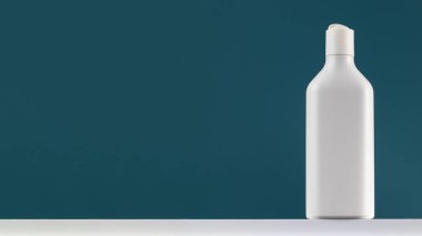 Beyaz bir rafta kozmetik aksesuarları olan beyaz bir şişe. Duş jeli ya da amblemi olan bir şampuan. Pankart. Boşluğu kopyala