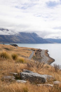 Bir dağ gölü manzarası, dağlar ve Yeni Zelanda 'nın güney adasında dolambaçlı bir yol. Doğanın güzel manzarası.