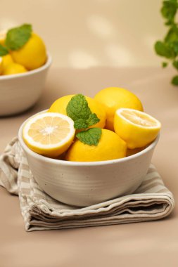 Seramik bir tabakta, üzerinde güneşten gelen gölge desenli bir nane filizi olan yeşil, olgun limonlar. Sulu limonlar.