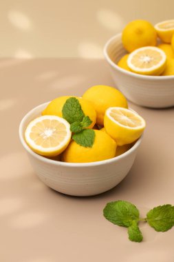  Seramik bir tabakta, masada bir tutam nane ile olgunlaşmış limonlar. Sulu limonlar