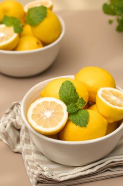  Seramik bir tabakta, masada bir tutam nane ile olgunlaşmış limonlar. Sulu limonlar