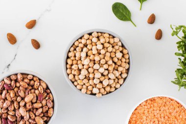 Hafif bir arka planda nohut, fasulye, bezelye ve ıspanak. Sebze proteini konsepti, sağlıklı vejetaryen yiyecekler. Üst görünüm