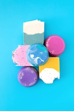 Mavi arka planda el yapımı renkli parlak sabun parçaları. Doğal sabun kavramı.