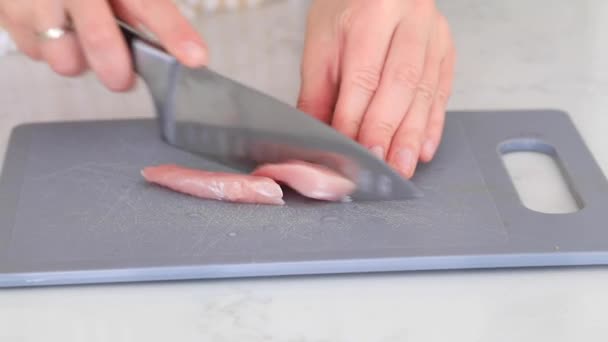 女性はキッチンに立って テーブルの上にボード上の生の豚肉の一部をカットします 調理工程 — ストック動画