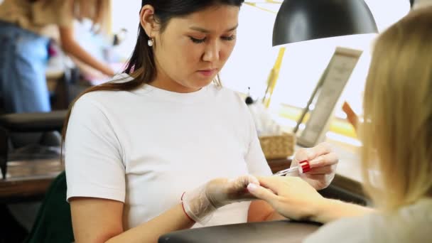 美甲师把油涂在病人的角质层上 并在美甲术后按摩她的手 美容院的概念 — 图库视频影像