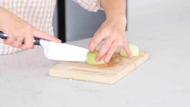 女性は台所に立って テーブルの上にボード上のタマネギをカットします 調理工程 — ストック動画