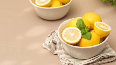  Seramik bir tabakta, masada bir tutam nane ile olgunlaşmış limonlar. Sulu limonlar