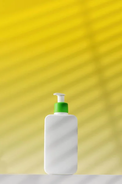 在黄色背景下 用化妆品对面部和身体进行皮肤护理的白色配药机的模型 洗面乳 洗面水 — 图库照片