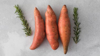 Gri arka planda çiğ patates. Turuncu kumara, tatlı patates. Kök ekin hasadı. Sağlıklı beslenme kavramı.