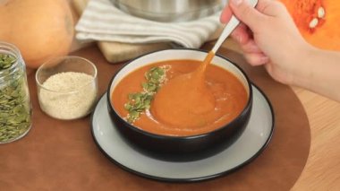 Bir kadın kaşıkla kabak çorbasını karıştırıyor. Sonbahar menüsü, basit sebze tarifleri. Video