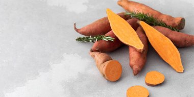 Çiğ patatesler bir bütün ve gri bir arka planda kesilmiş. Portakallı kumara, tatlı patates. Kök ekin hasadı. Sağlıklı beslenme kavramı. Uzayı kopyala Pankart