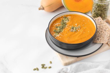 Patates püresi ve çekirdekli bir kase balkabağı çorbası bir ışık masasında duruyor. Sonbahar menüsü konsepti. Kolay vejetaryen tarifleri. Boşluğu kopyala