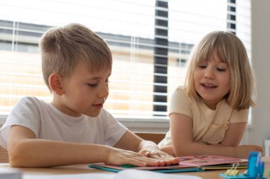 Erkek ve kız kardeş birlikte evde dostça bir eğitim kitabı okudular. Mutlu çocukluk kavramı. 
