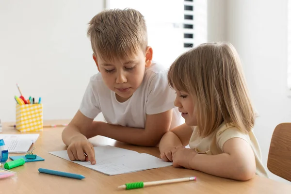 The older brother teaches the younger sister to read letters. The concept of brother and sister, home schooling.