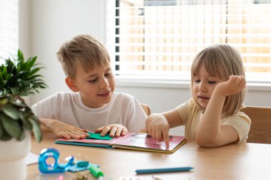 Erkek ve kız kardeş birlikte evde dostça bir eğitim kitabı okudular. Mutlu çocukluk kavramı. 
