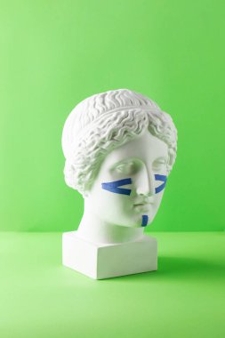 Yeşil arka plandaki büstteki yüz için mavi kasetler. Cerrahi olmayan yüz gerdirme, gençleştirme kavramı..