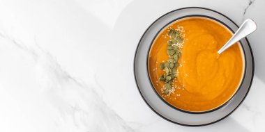 Patates püresi ve çekirdekli bir kase balkabağı çorbası bir ışık masasında duruyor. Sonbahar menüsü konsepti. Kolay vejetaryen tarifleri. Boşluğu kopyala