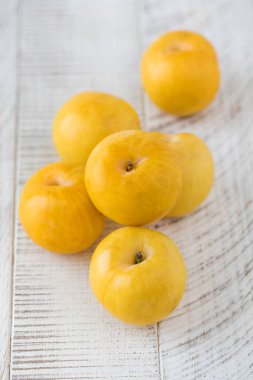 Beyaz ahşap bir masada olgun sarı erik. Hasat konsepti, meyveler..