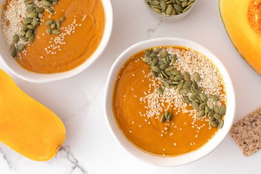 Kabak çorbası püresi, balkabağı ve susam tohumlu tabaklar. Sonbahar menüsü konsepti. Kolay vejetaryen tarifleri, ezilmiş çorba..