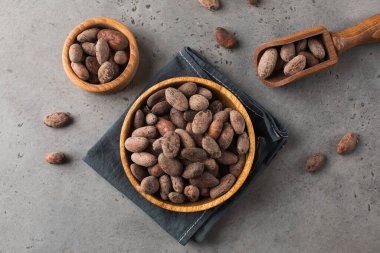 Koyu gri arka planda, tahta tabakta kakao çekirdeği. Doğal kavrulmuş kakao çekirdeği..