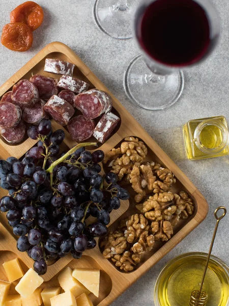 Snacks for wine in a wooden menagerie. Cheese, sausages, berries in a wooden plate, festive serving of snacks.